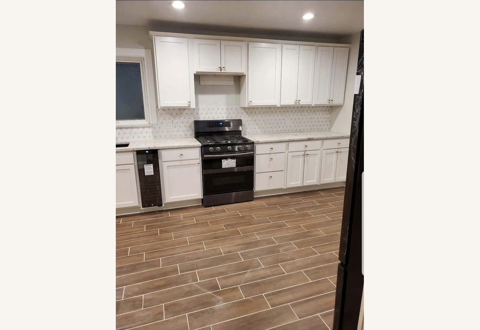 Reliable Renovators kitchen after photo with white cabinets tile floor and updated fireplace in Metro Detroit