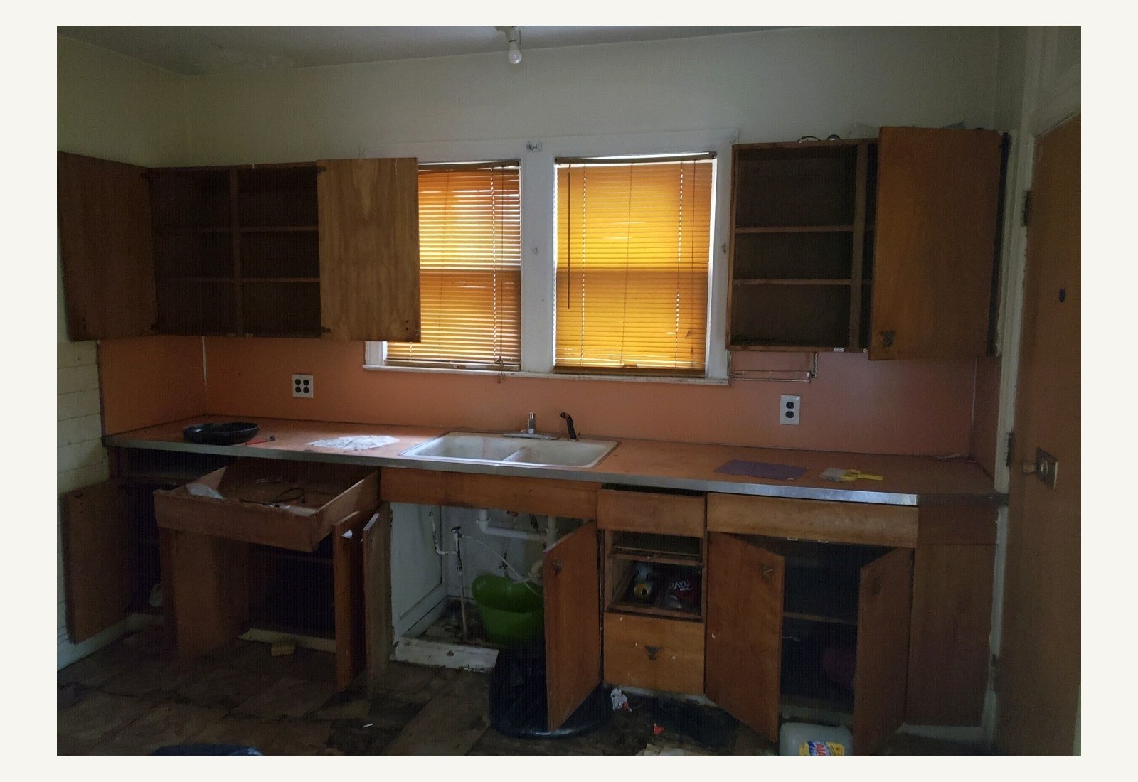 Reliable Renovators kitchen before photo with original open cabinets and sink wall in Metro Detroit